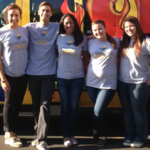 Group of five students standing in front of a van