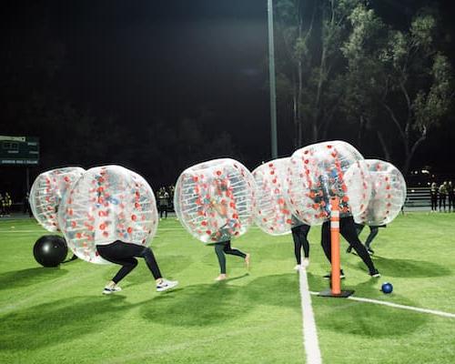 People playing soccer in inflatable bubbles